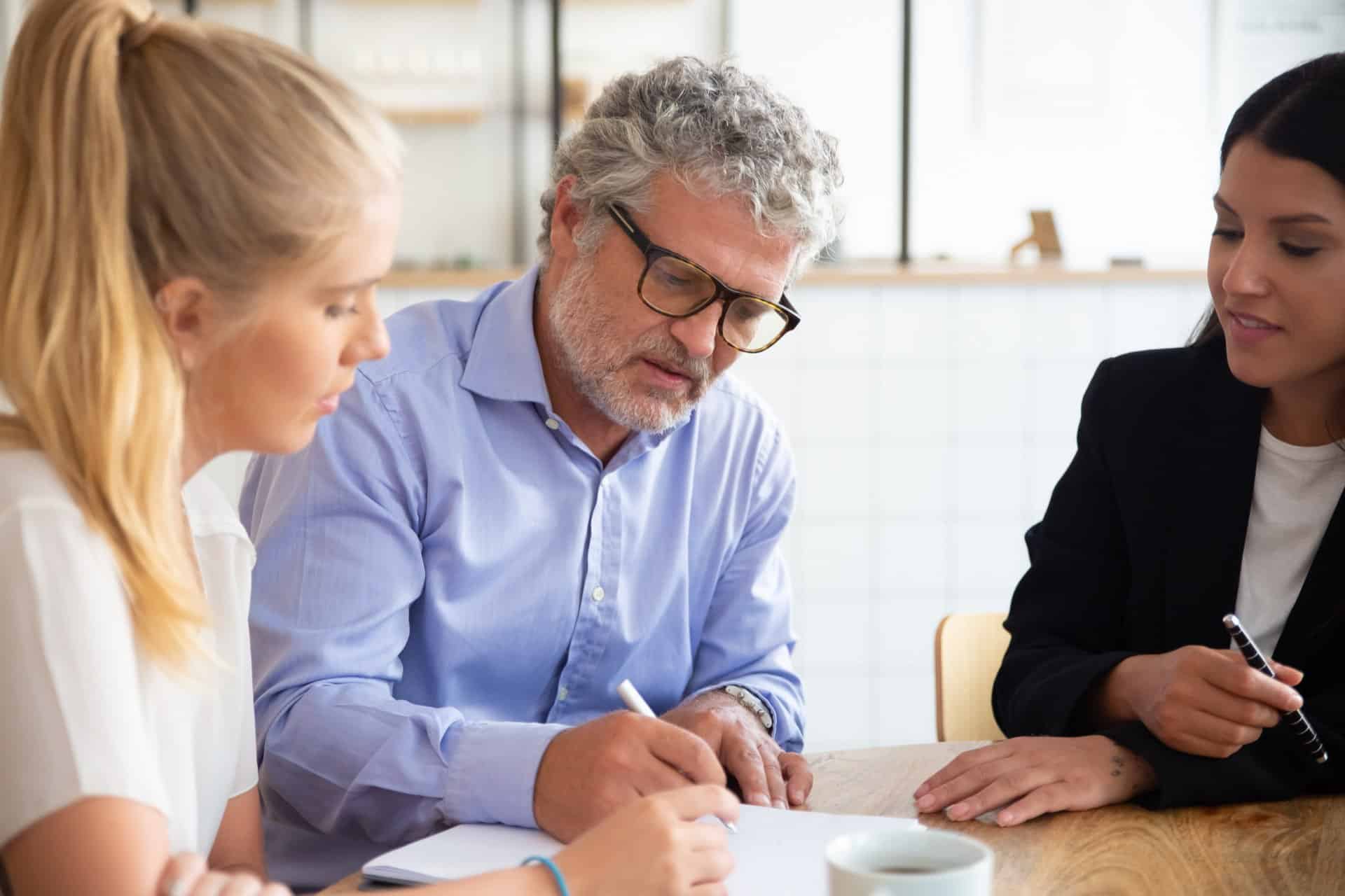 focused young mature customers meeting with agent signing insurance agreement